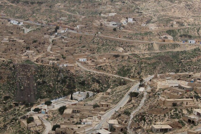 A hilly village with narrow roads and scattered buildings. 4