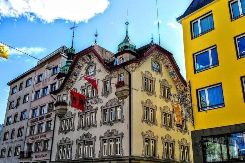 A historic building with ornate architecture, a prominent 'THAUS' sign, and a red flag. 4