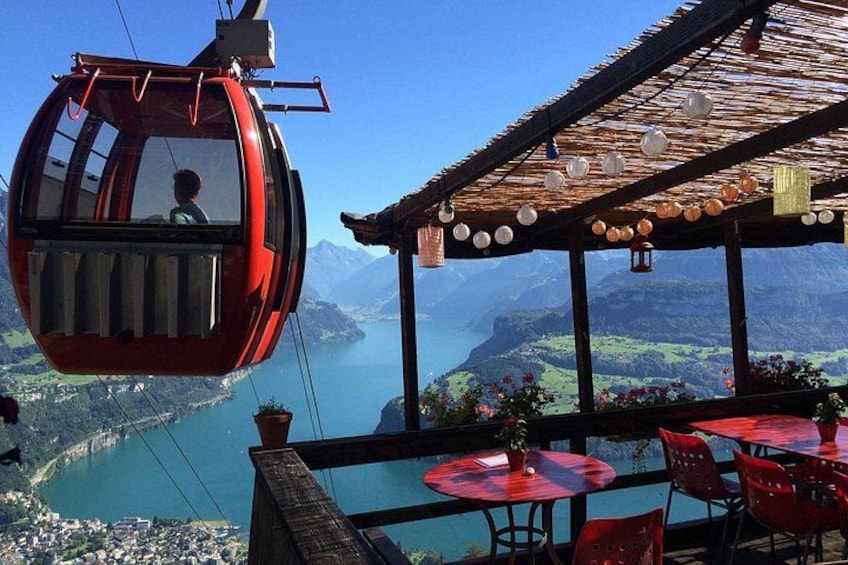 A red cable car, a wooden pergola with hanging lanterns, and a view of a lake and mountains. 3