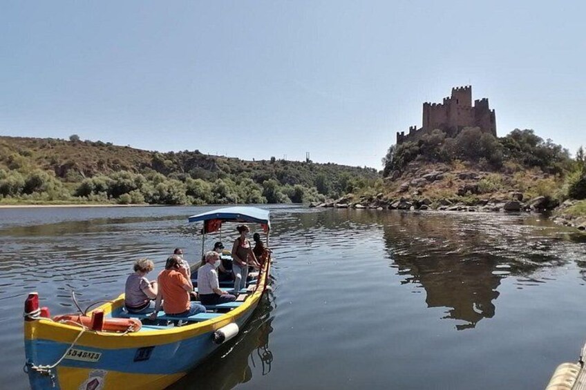 A group of people in a boat on a calm river, a castle on a hill in the background. 2