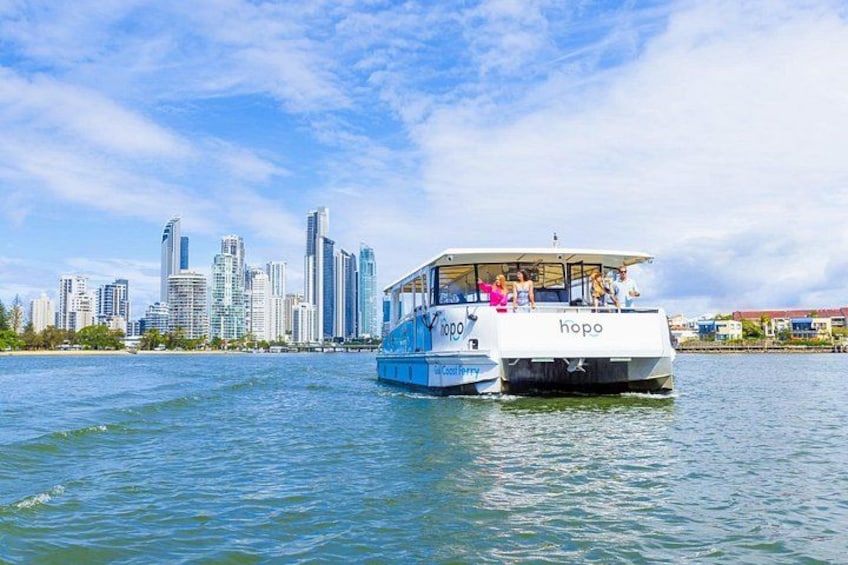 A boat named 'Hopo' on water with a city skyline in the background. 1