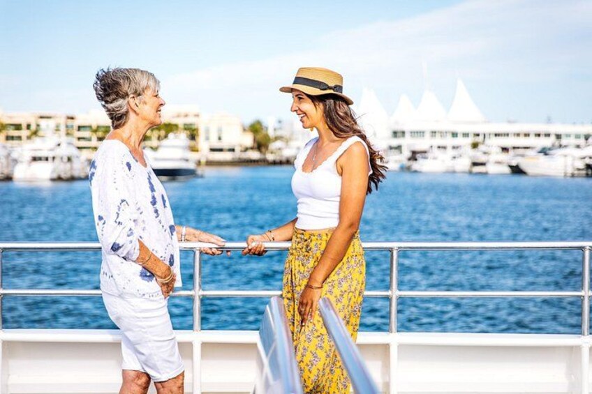Two people on a boat with a marina and boats in the background. 2