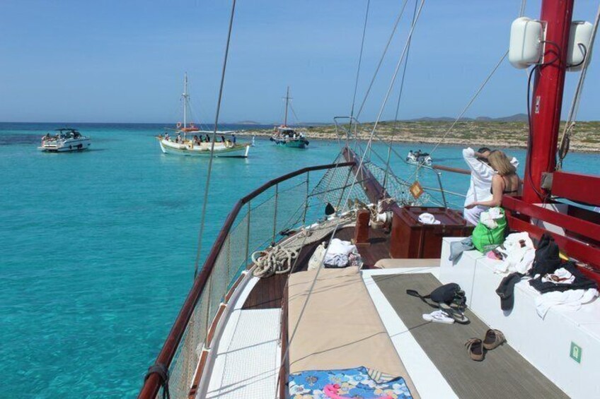 A boat deck with a person sitting, a net, and several boats in the background. 3