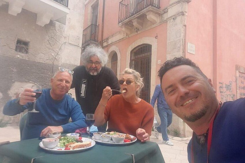 Un grupo de personas cenando al aire libre en una mesa con comida y bebidas. 1