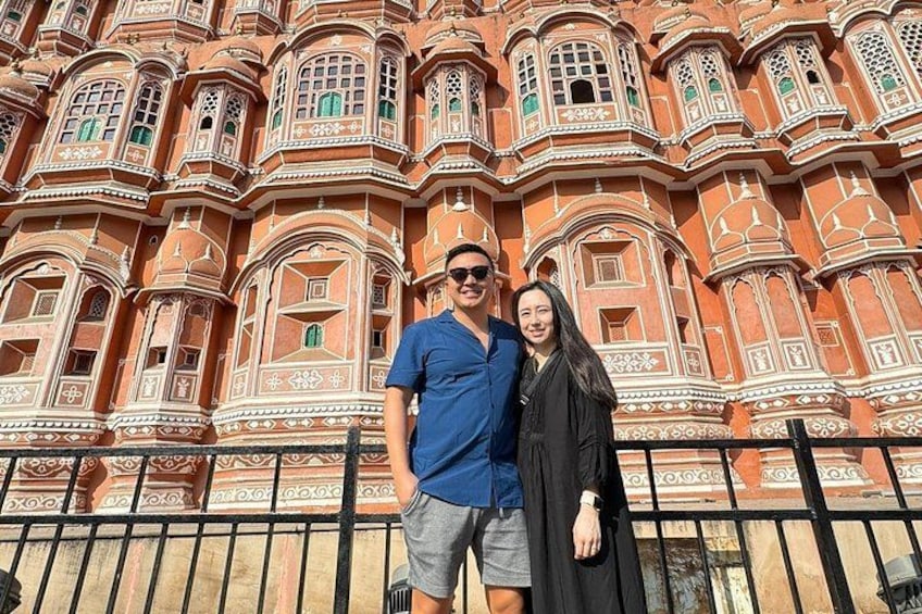 Un uomo e una donna in piedi di fronte a un grande edificio sfarzoso, caratterizzato da dettagli architettonici elaborati. 5
