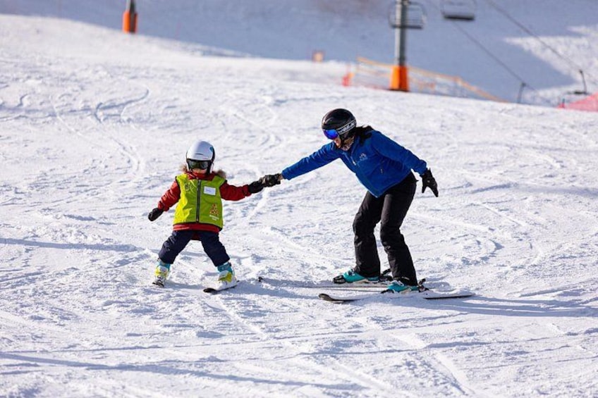 Un enfant et un adulte, tous deux équipés de skis, sur une pente enneigée. 4