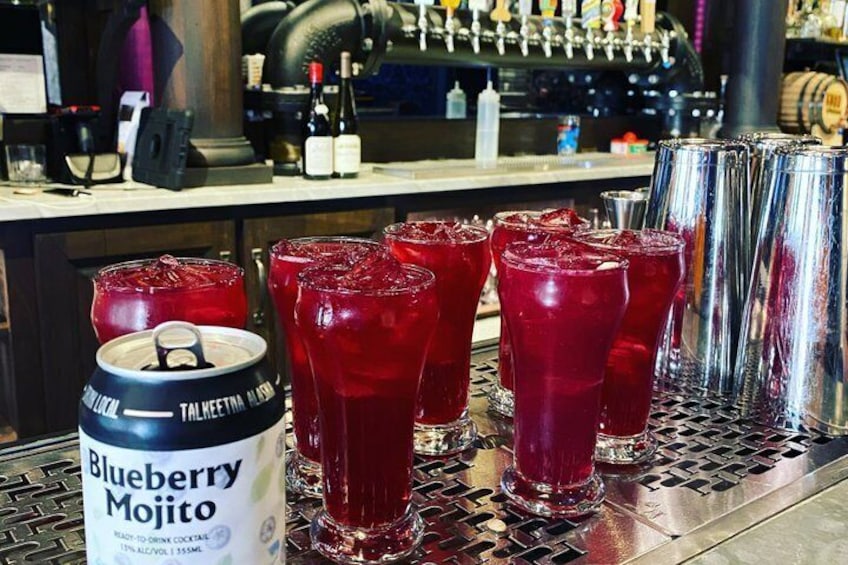 En bar med glas med rød drik, en dåse Blueberry Mojito og et fadølsanlæg. 4