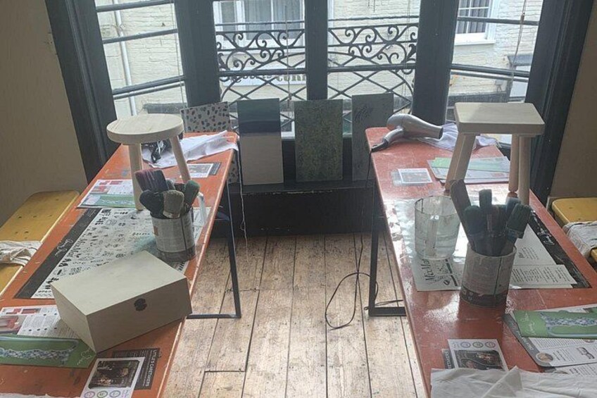 A wooden table with papers, a box, and a cup with pens. 3