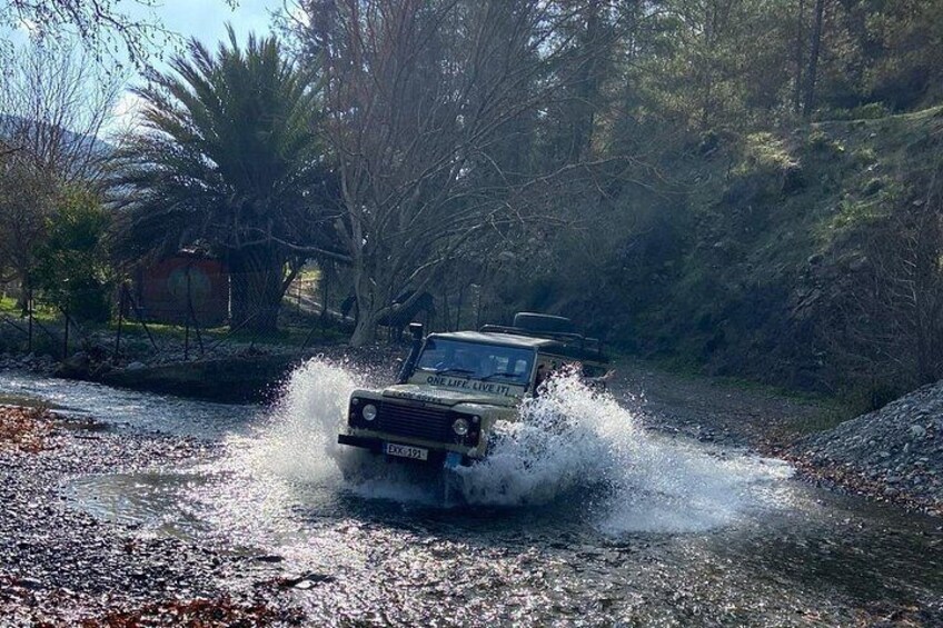 Ein Fahrzeug durchfährt eine flache Wasserstelle und wirbelt dabei Wasser auf. 2