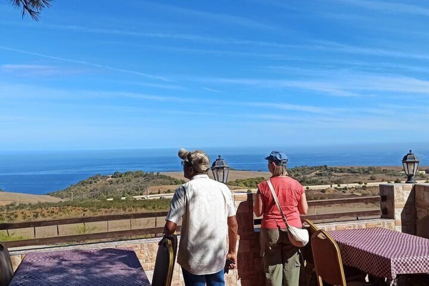 A coastal overlook with a view of the ocean, a wooden fence, and a checkered tablecloth. 5