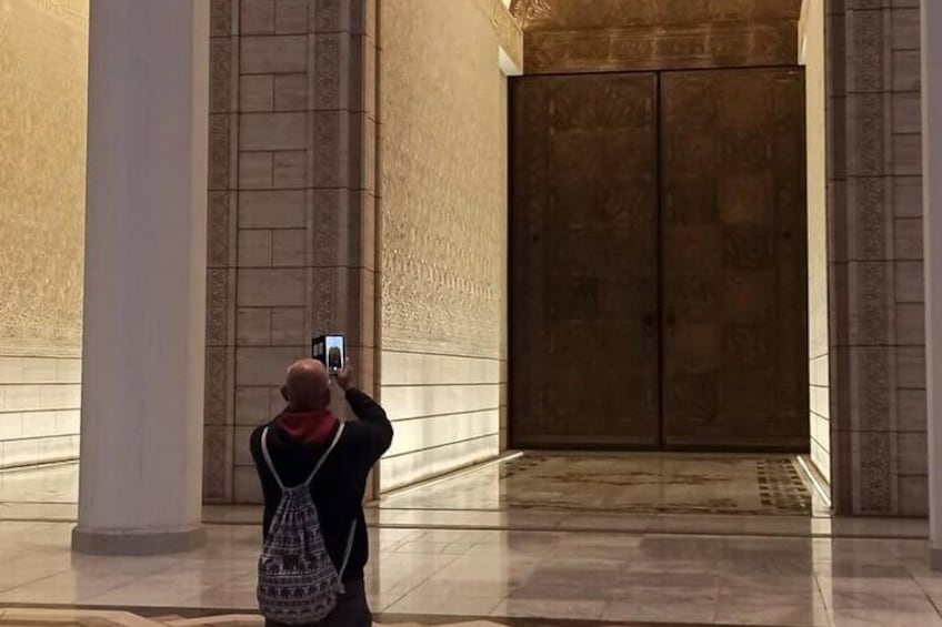 A person taking a photo with a smartphone in a building with large columns and a double door. 3