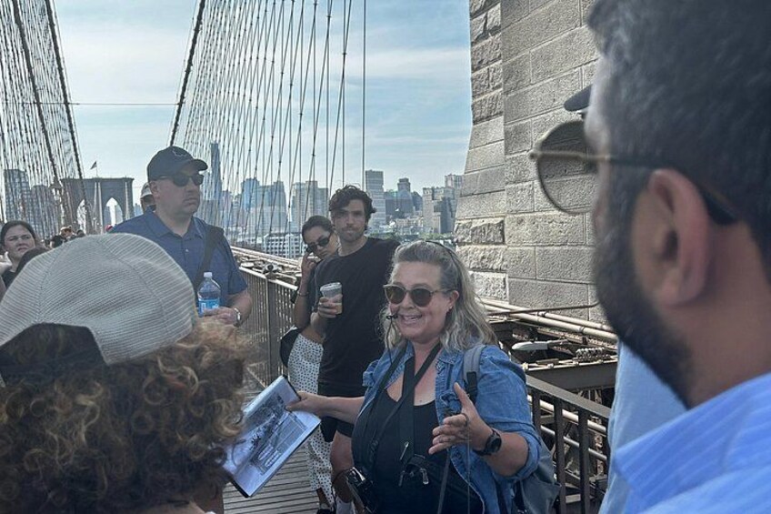 Eine Gruppe von Menschen auf einer Brücke, im Hintergrund die Skyline einer Stadt. 4