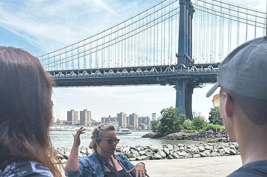 A group of people standing by a waterfront with a large bridge in the background. 4
