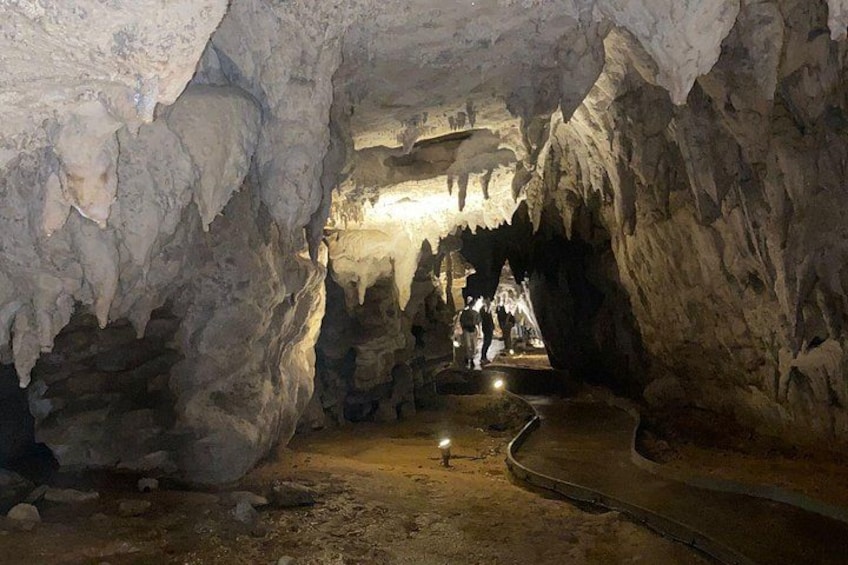 Une grotte ornée de stalactites et de stalagmites, un sentier et des visiteurs. 4