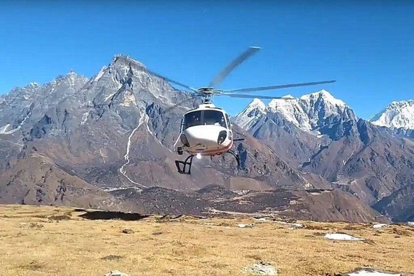 A helicopter flying over a mountainous landscape with snow-capped peaks in the background. 4