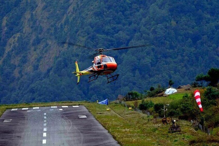 A helicopter landing on a runway with a mountainous backdrop. 5