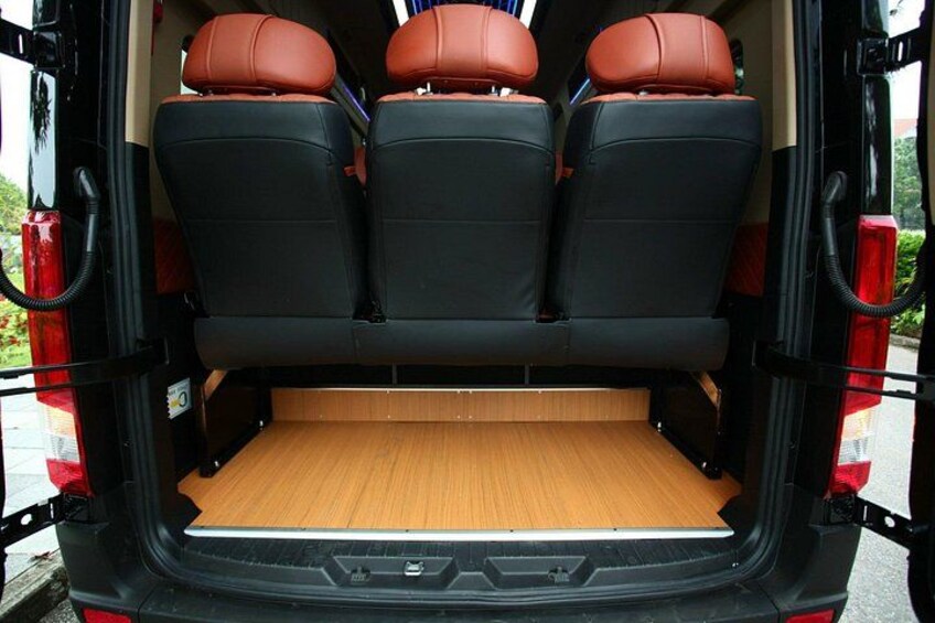 The back of a vehicle with three black seats and a wooden floor. 4