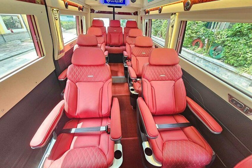 A train interior with red leather seats and a 'Luxury' sign. 1