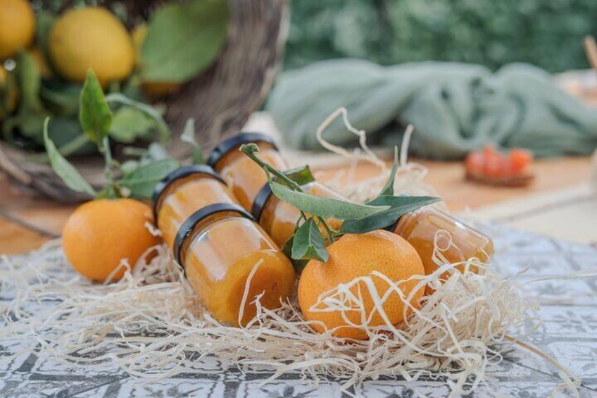 Arance in bottiglie di vetro su una superficie ricoperta di paglia, con un cesto di limoni sullo sfondo. 5