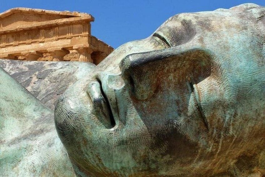 A bronze statue of a sleeping lion with a building in the background. 1