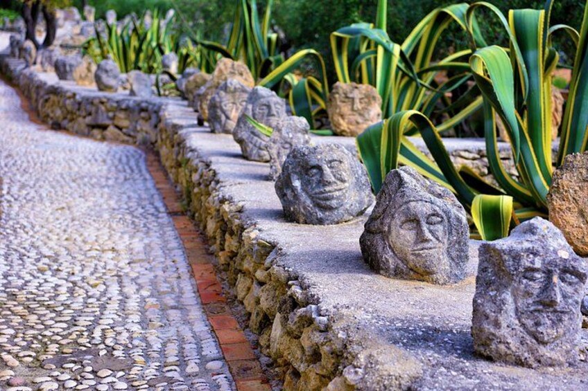 A pathway lined with stone sculptures and agave plants. 3