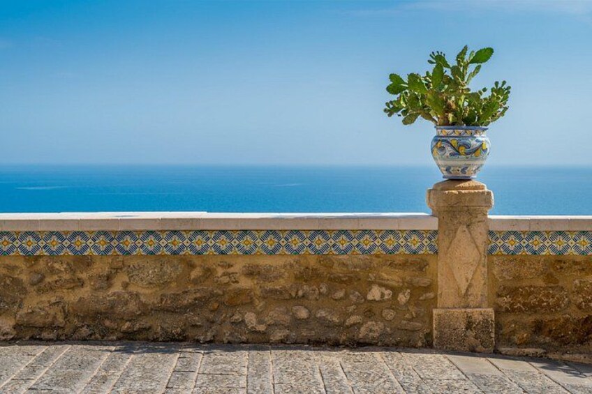 A potted plant on a stone balustrade overlooking the sea. 5