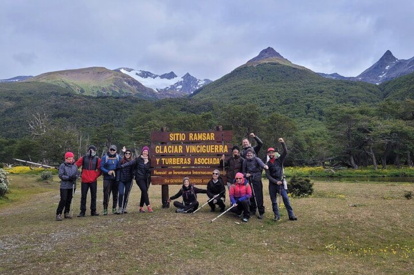 A group of people posing in front of a sign with a mountainous landscape in the background. 1