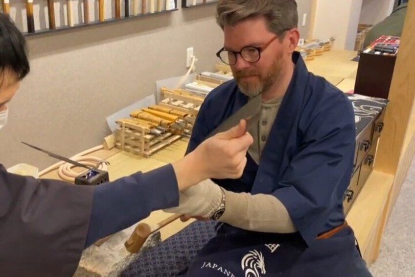 Une personne tenant un couteau, peut-être dans un atelier ou lors d’une démonstration. 4