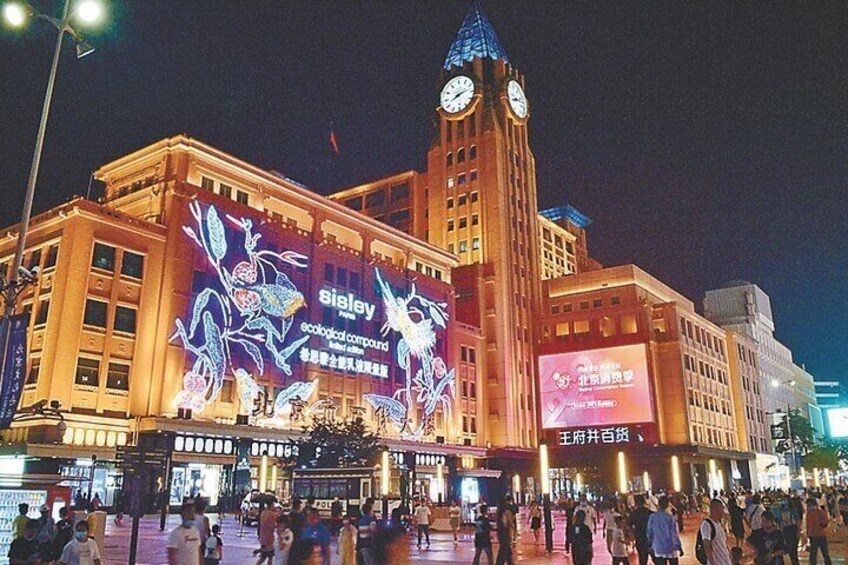 A large building with a clock tower and illuminated advertisements. 2