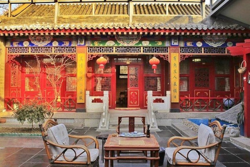 A traditional Chinese building with red doors and yellow banners, a tiled patio with wicker furniture, and a decorative railing. 4
