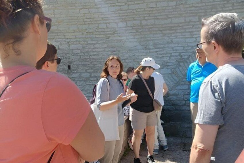 A group of people standing outdoors, possibly at a historical site with stone walls. 5
