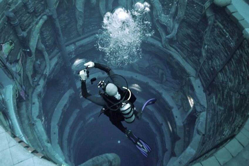 A diver in a large underwater chamber with a helmet and fins. 3