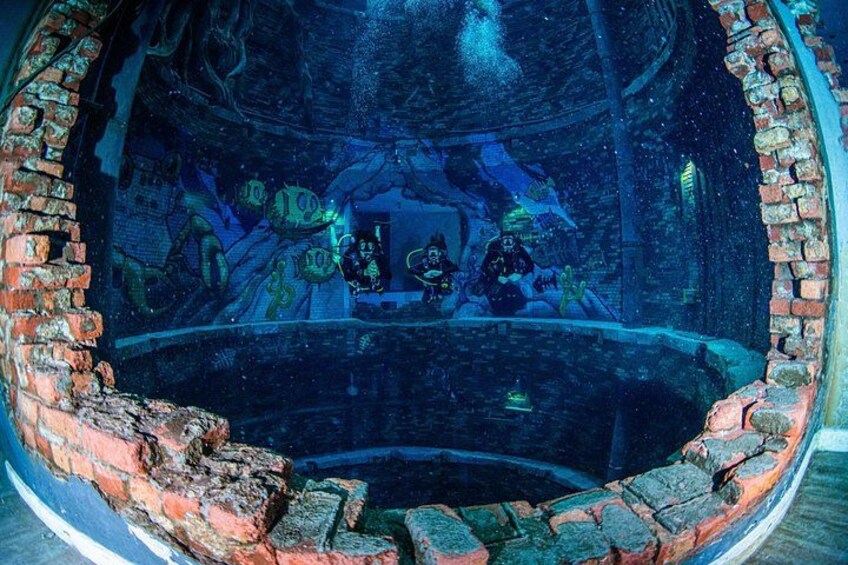 An underwater scene with divers, a brick structure, and marine life. 5