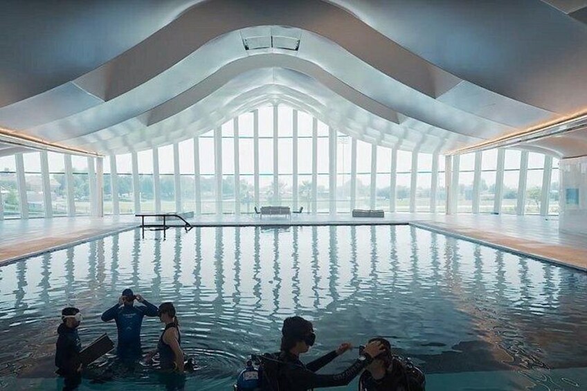 An indoor swimming pool with a high ceiling and large windows. 4