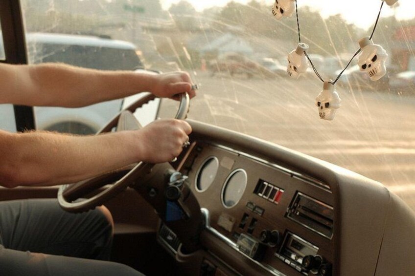 A person driving a vehicle with a steering wheel, dashboard, and a rearview mirror. 2