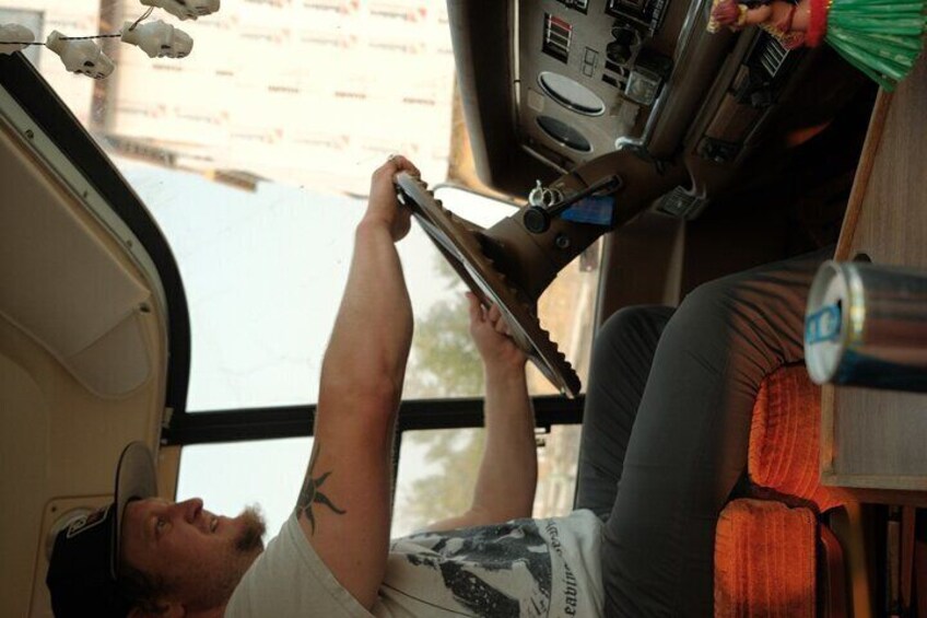 A person lying on a bus seat, holding a device, with a window and a can on the table. 2