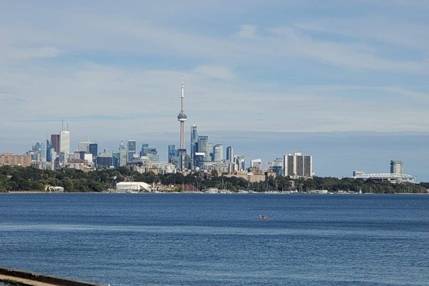 A city skyline with a prominent tower, a body of water in the foreground, and a clear sky. 3