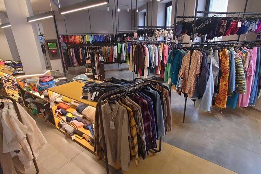 A clothing store with racks of clothes and folded items on tables. 2