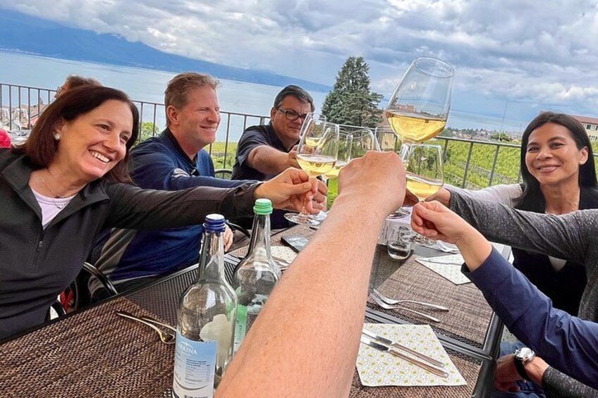 A group of people toasting with wine glasses at a table with a scenic view. 1