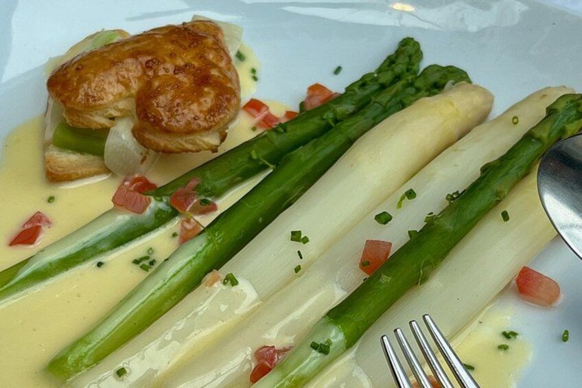 A plate with asparagus, a pastry, and a creamy sauce. 2