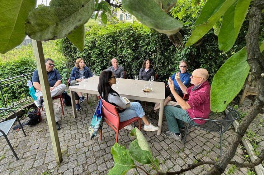 A group of people sitting around a table outdoors, engaged in conversation. 4