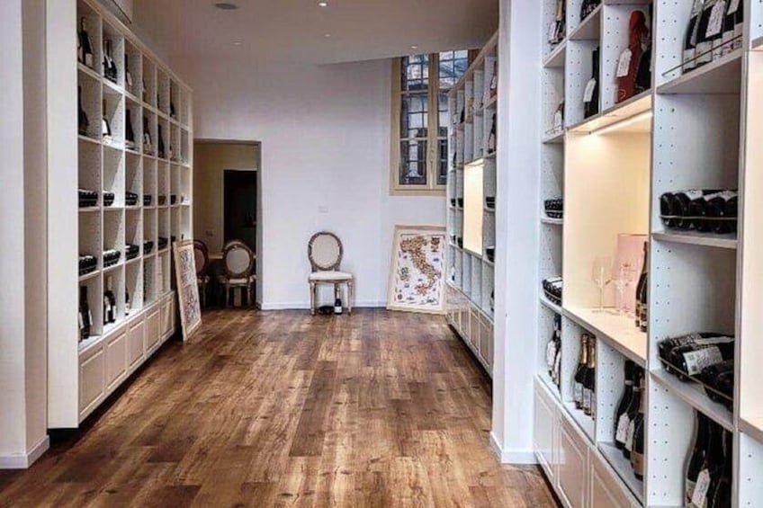 A spacious room with wooden flooring, white shelving units filled with shoes, and a framed artwork on the wall. 2