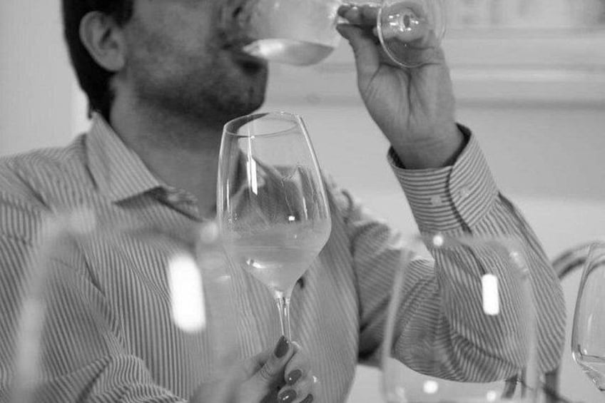 A person holding a wine glass, wearing a striped shirt, in a setting with other wine glasses visible. 4