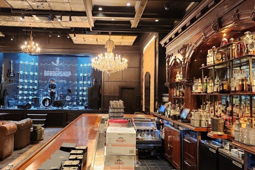 Un barbero con escenario, una araña y una zona de bar con botellas. 3