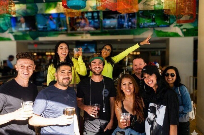 A group of people holding drinks in a bar with colorful decorations. 5
