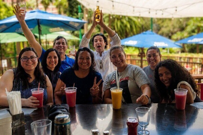 A group of people at an outdoor dining area with drinks and umbrellas. 4