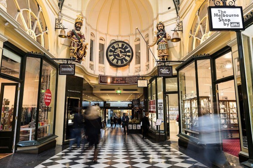 A shopping corridor with a checkered floor, a large clock, and statues. 2