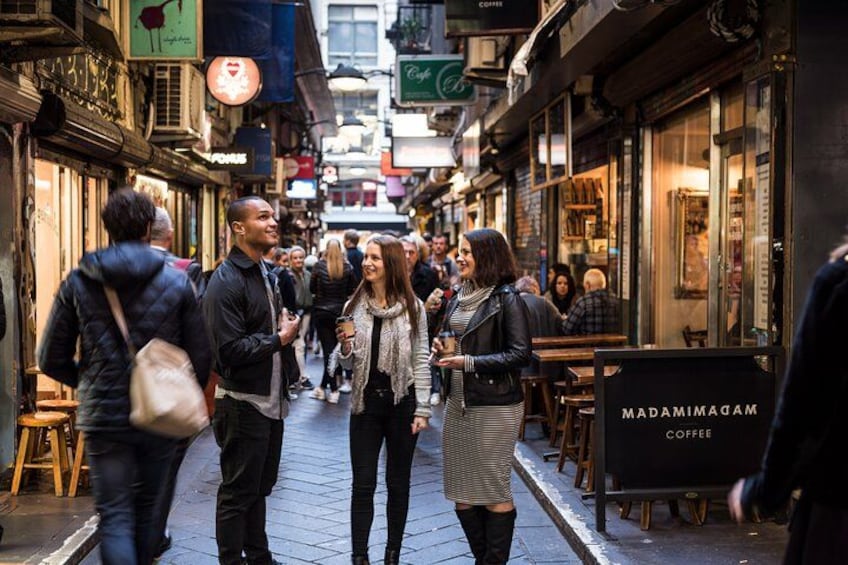 A busy street with people walking, cafes, and a sign for Madam Madam Coffee. 5