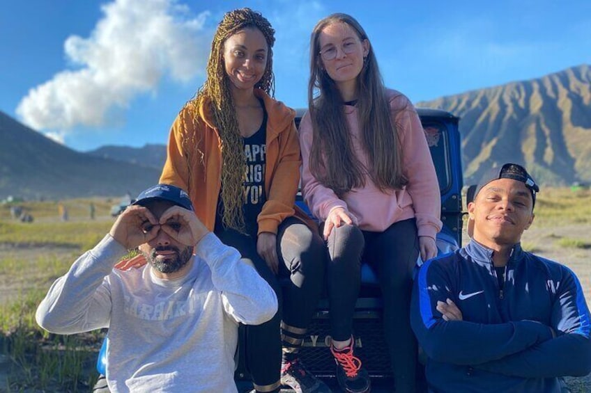 Four people sitting outdoors with mountains in the background. 1