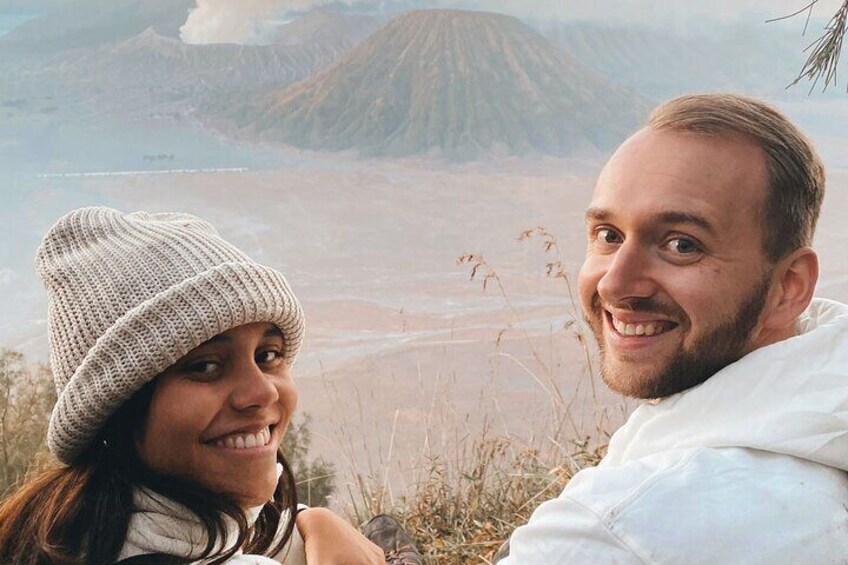 A person wearing a white jacket and a beanie, with a mountainous landscape in the background. 5